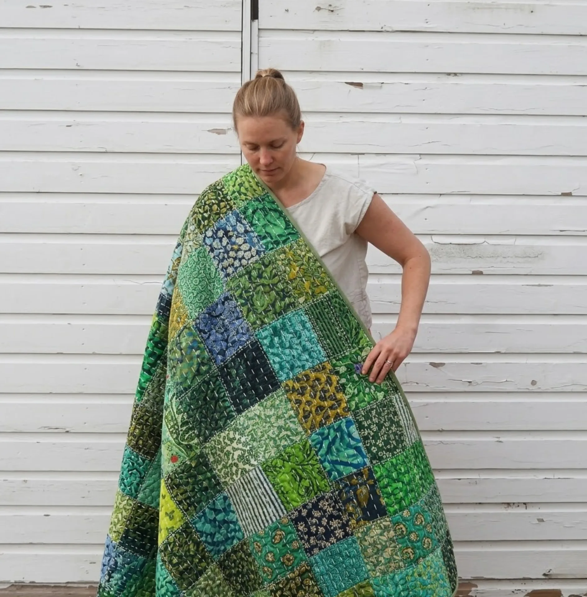 Woman holding a large vintage patchwork quilt — perfect upcycled fabric for the LU2COHOUSE Siena Quilt Coat sewing pattern